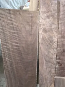 Raw curly walnut timber with smaller figured walnut boards next to it.
