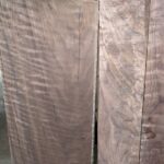 Raw curly walnut timber with smaller figured walnut boards next to it.