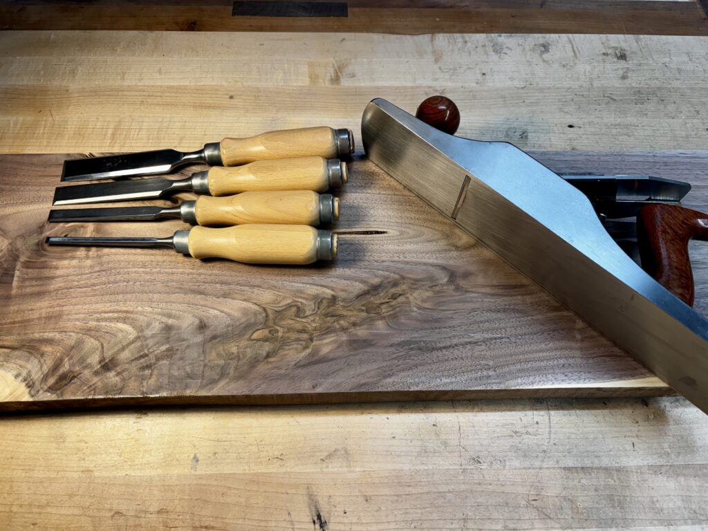 Woodworker’s hand tools on a figured walnut timber.